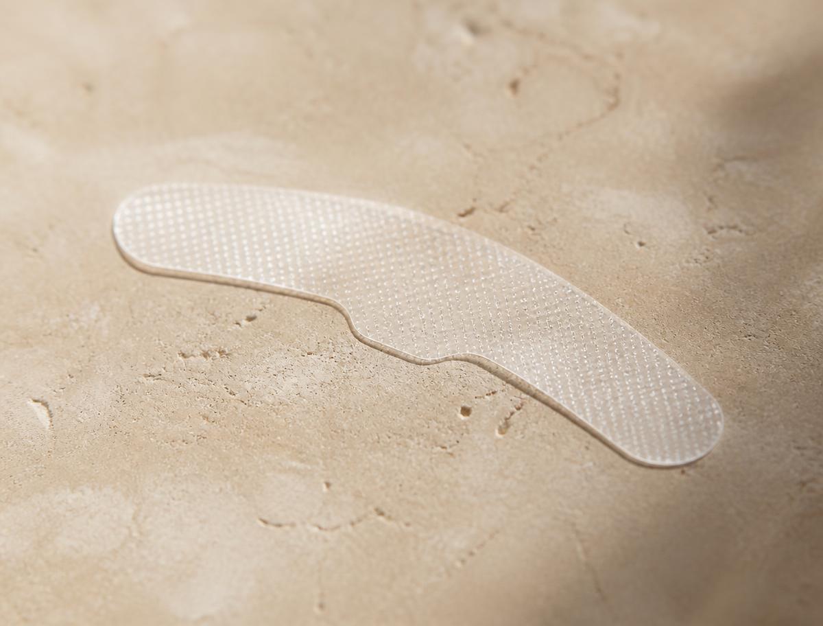 Ultra-thin translucent whitening strip resting on a stone surface